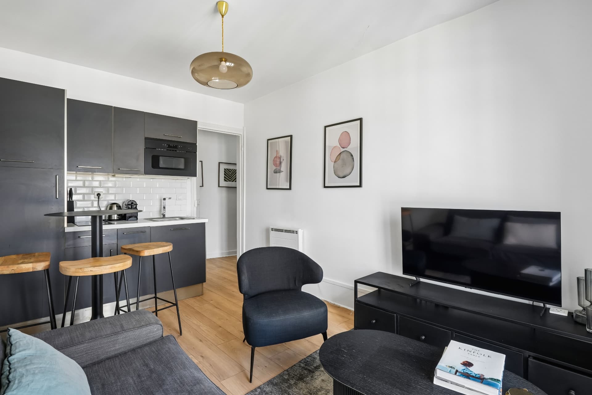 Cuisine ouverte du lot 19 en gris anthracite avec tabourets en bois et fauteuil bleu