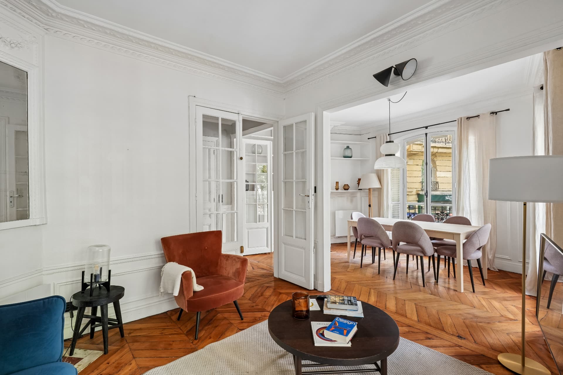 Séjour du lot 7 avec fauteuil en velours et portes vitrées vers la salle à manger