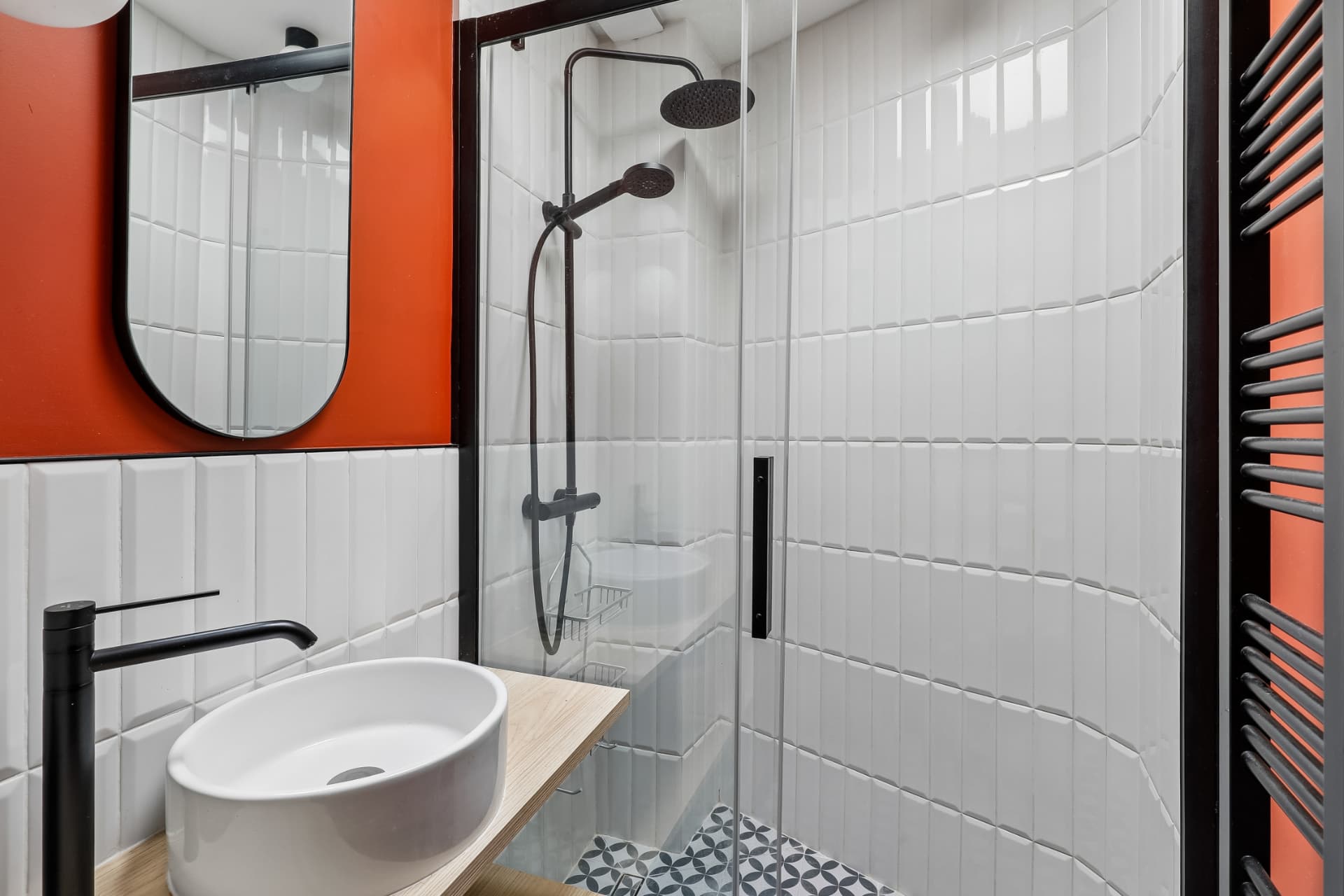 Salle d'eau du lot 20 carrelée de métro blanc, douche vitrée et touches orangées