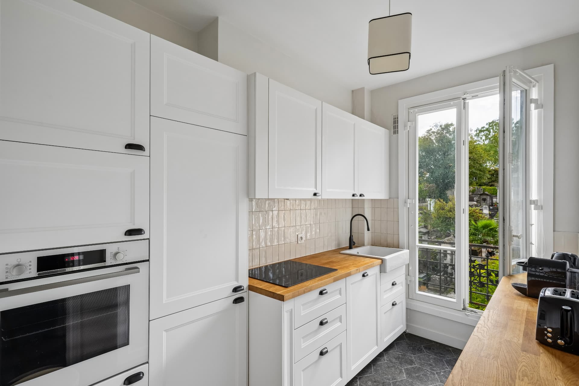 Cuisine équipée du lot 10, crédence beige et porte-fenêtre sur balcon