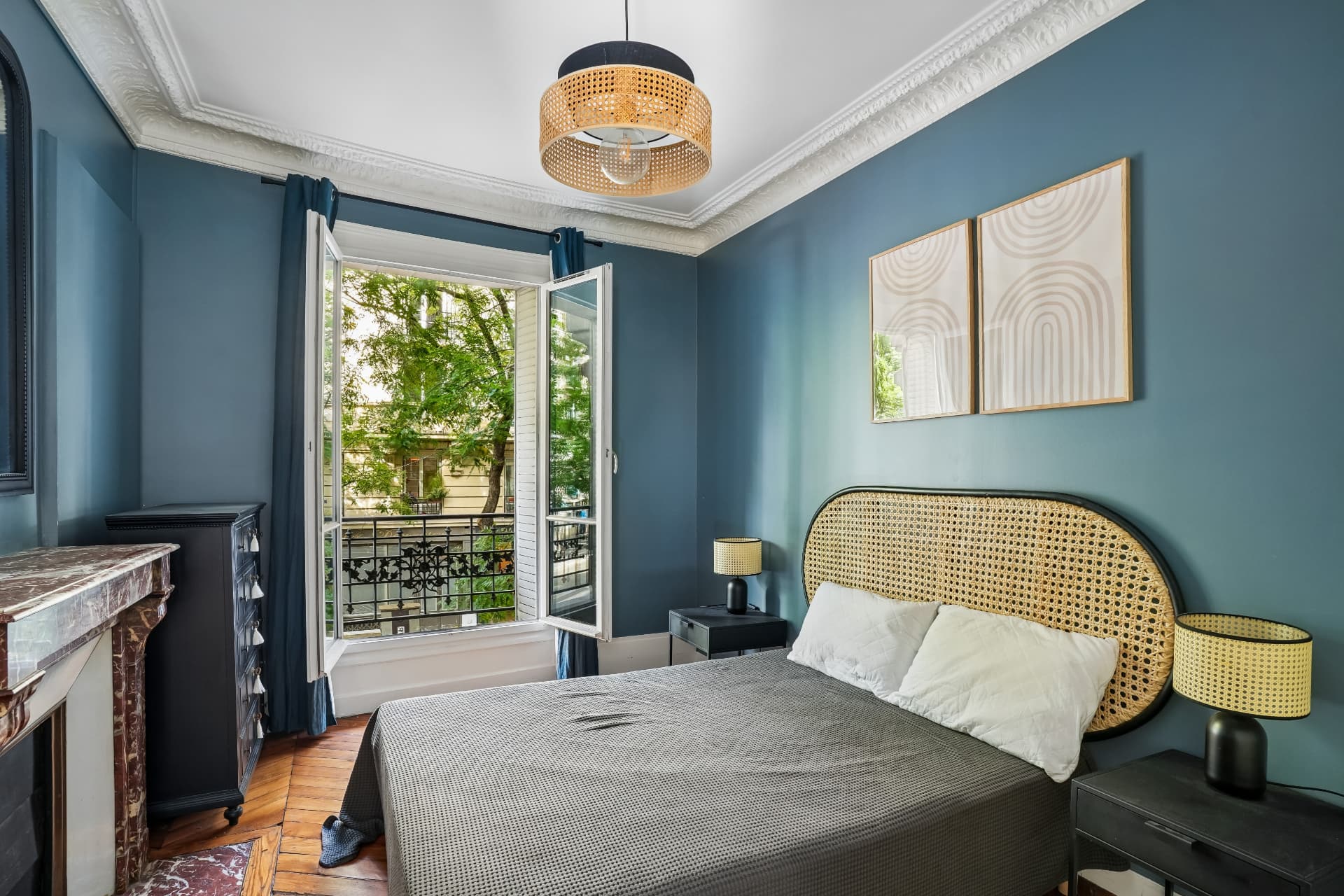 Chambre du lot 7 aux murs bleus, tête de lit en rotin, ouverte sur le balcon