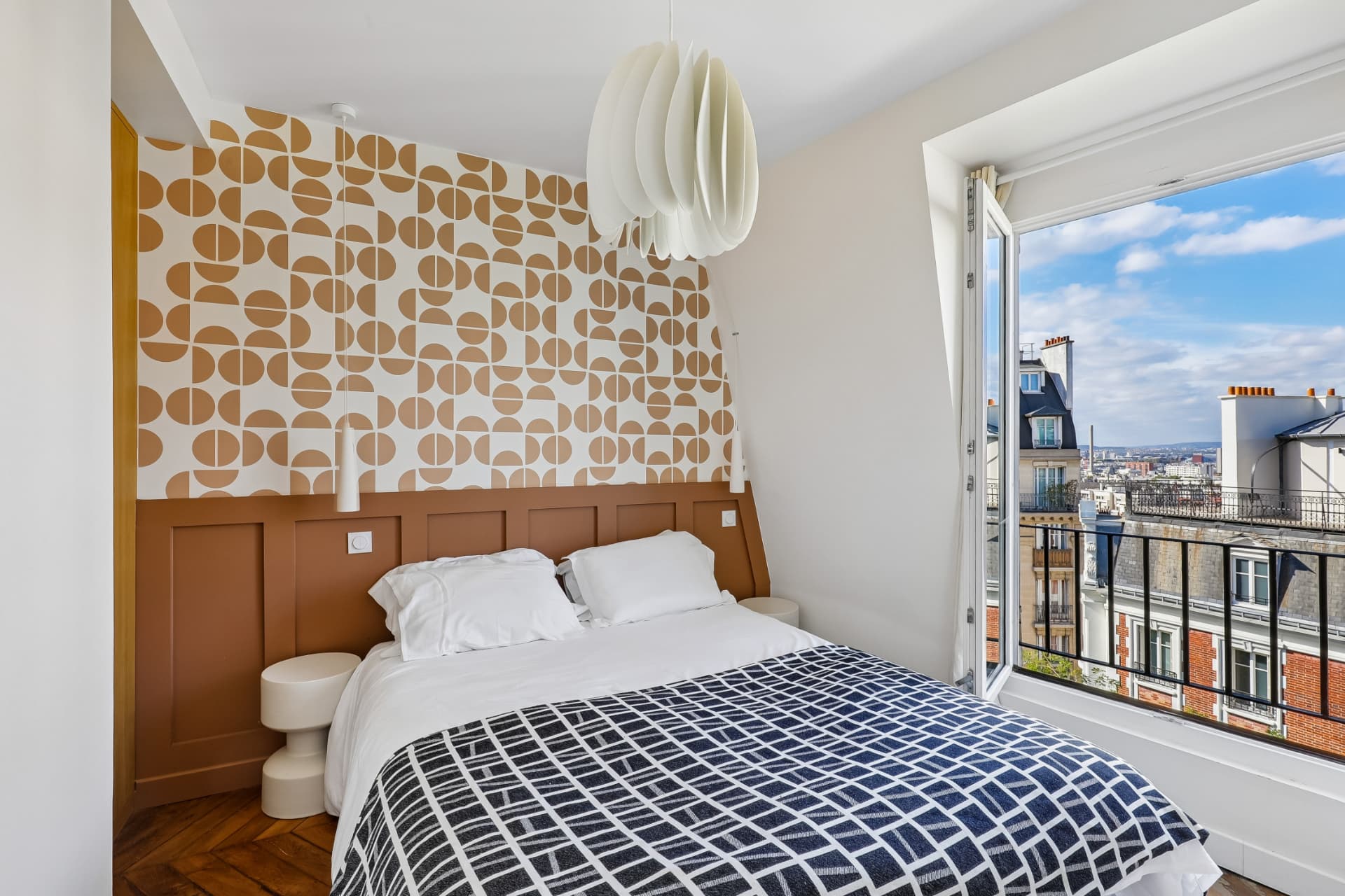 Chambre du lot 20 sous les toits avec papier peint géométrique ocre, parquet point de Hongrie et vue sur Paris