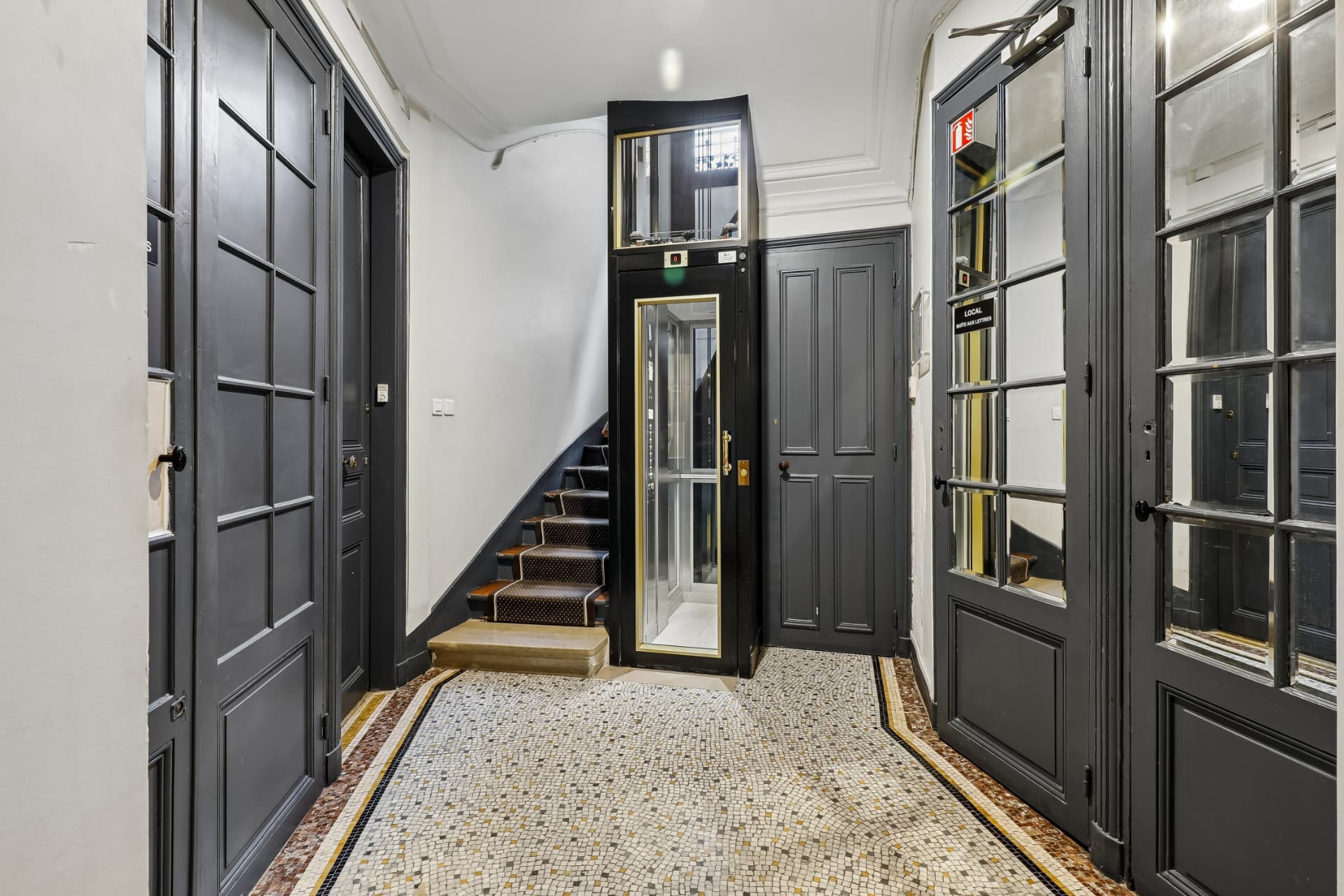 Hall d'entrée avec sol en mosaïque d'origine et portes noires vitrées