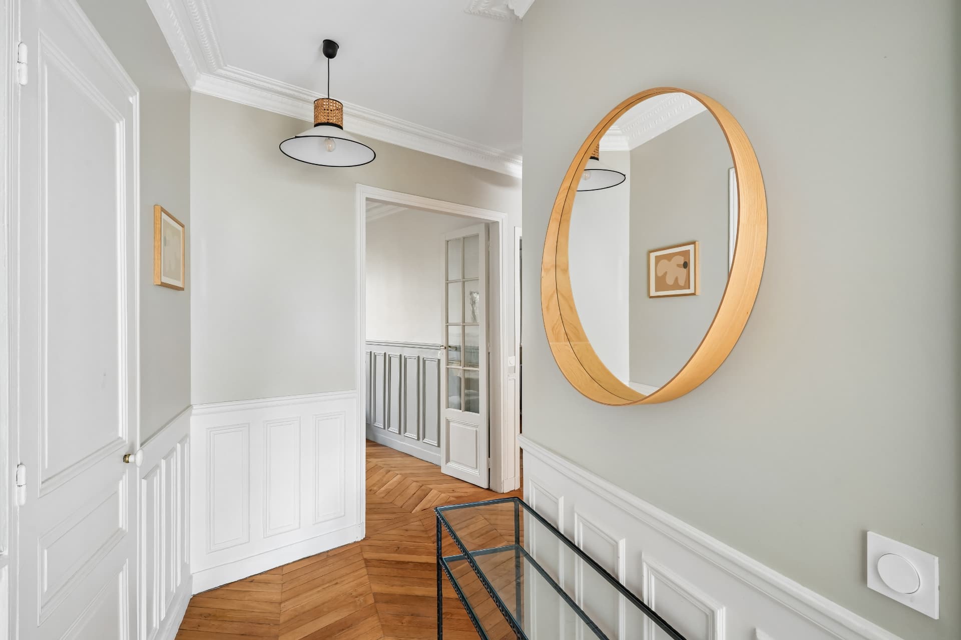 Entrée du lot 10 avec miroir rond, moulures et porte-fenêtre vitrée